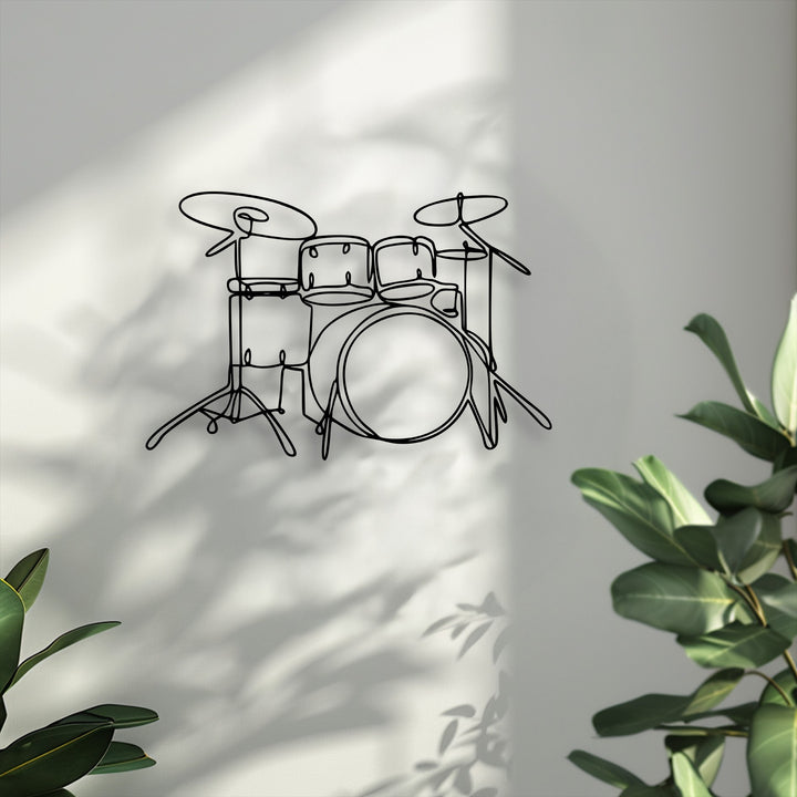 Muted color saturation emphasizes the sleek minimalist drum set decorative metal art, displayed on a soft-hued wall with gentle shadows and green leaves.