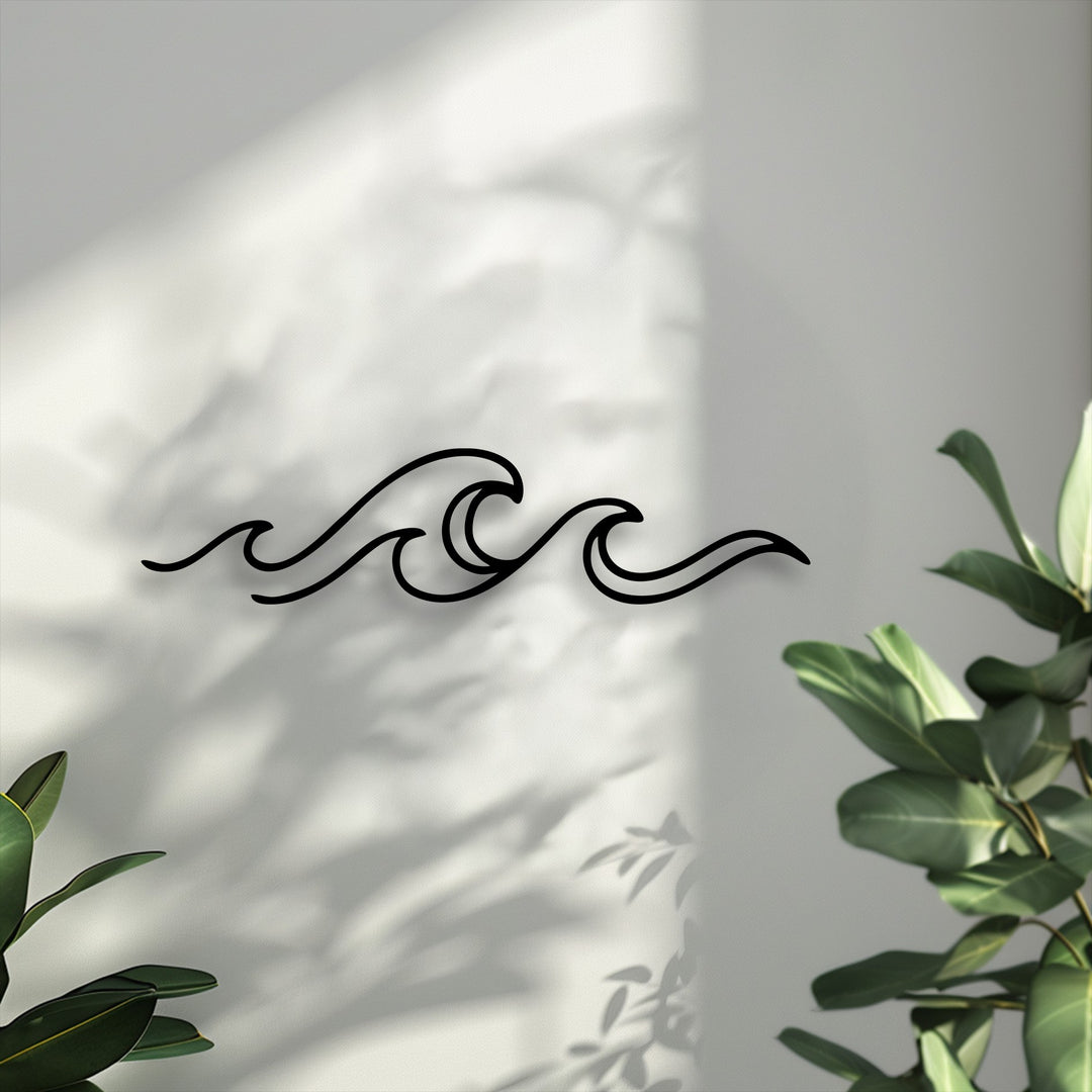 The focal point is a striking black minimal ocean wave metal artwork, elegantly displayed on a sunlit wall with soft plant shadows.