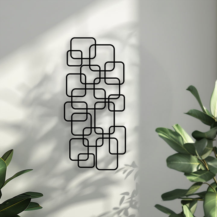 Vertically oriented metal art for wall featuring a modern geometric design of numerous interlocking rounded squares.