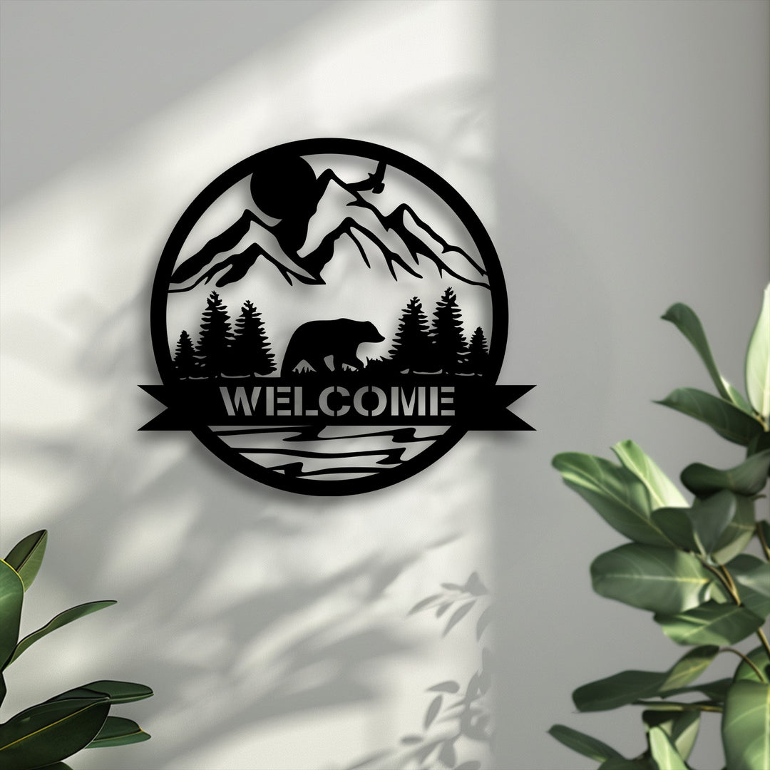 The subtle transition from light to deeper grey tones on the wall highlights the stark black silhouette of this mountain bear welcome metal wall decor.