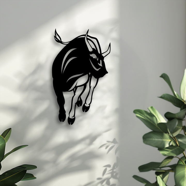 Organic forms define the muscular charging bull silhouette, casting dynamic shadows on the wall, a striking piece of metal art for wall.