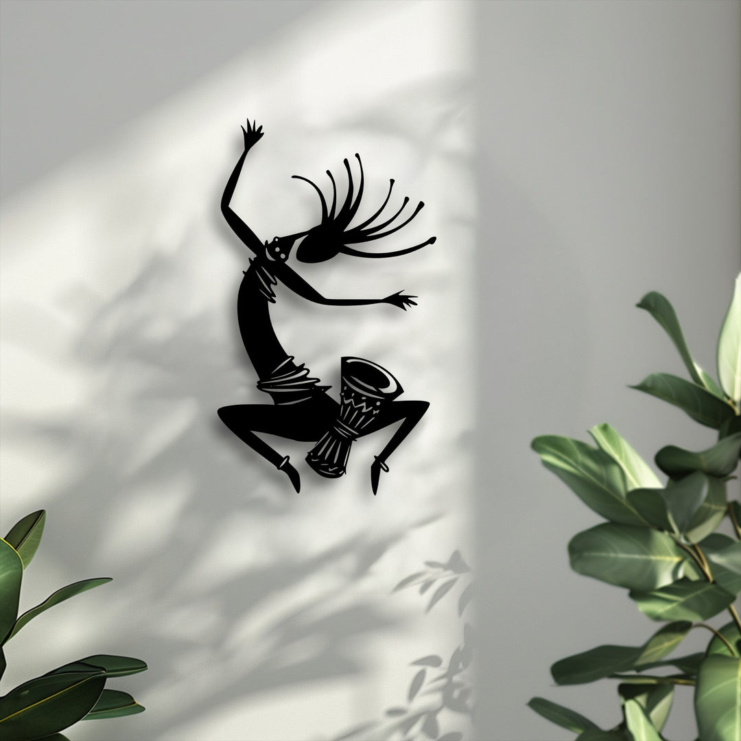 The striking color contrast between the dark tribal dancer metal artwork silhouette and the bright wall creates a dynamic visual.