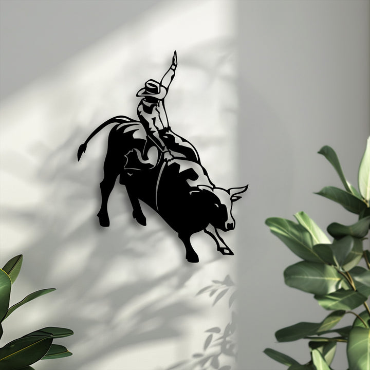 The darkest area forms a striking, intense silhouette of a rodeo cowboy on a bucking bull, an impressive decorative metal art.
