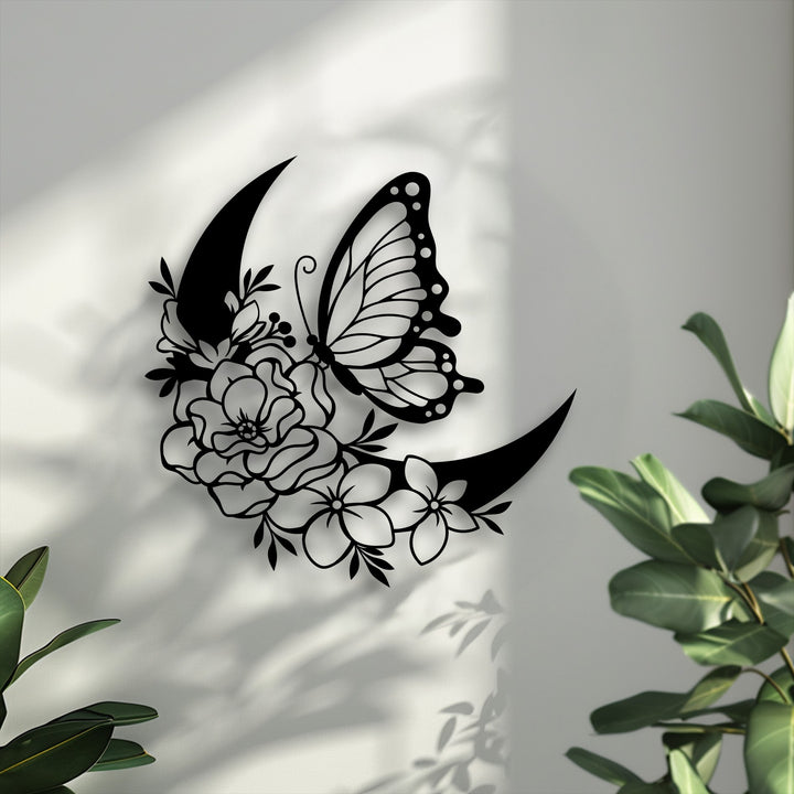 Lush green foliage softly frames a striking butterfly and floral crescent decorative metal art, casting intricate shadows.