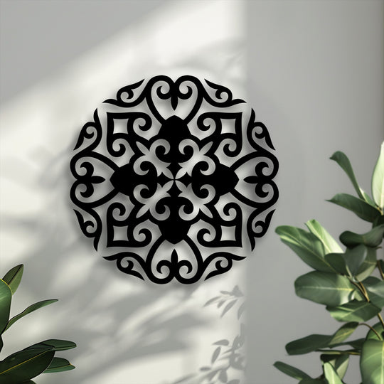 The striking color contrast of the black ornate floral mandala metal art for wall against the bright white background with natural shadows.