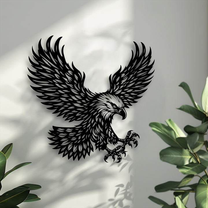 Soft, blurred green leaves gently frame the bold majestic eagle metal art for wall, set against a backdrop of diffused light and shadow.