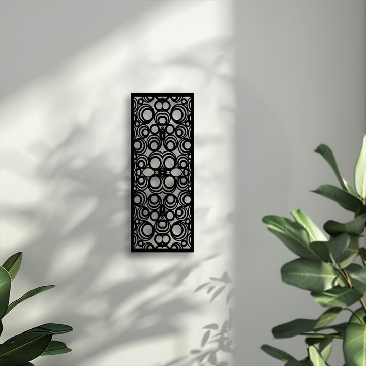 The gradual transition between sunlit white and soft gray shadows on the wall enhances the striking geometric circle pattern metal artwork.