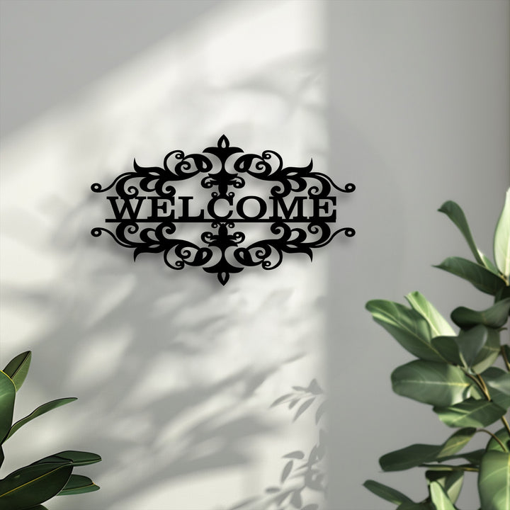 The abstract quality of the ornate decorative metal art welcome sign is highlighted by its intricate design and fluid shadows on the textured wall.
