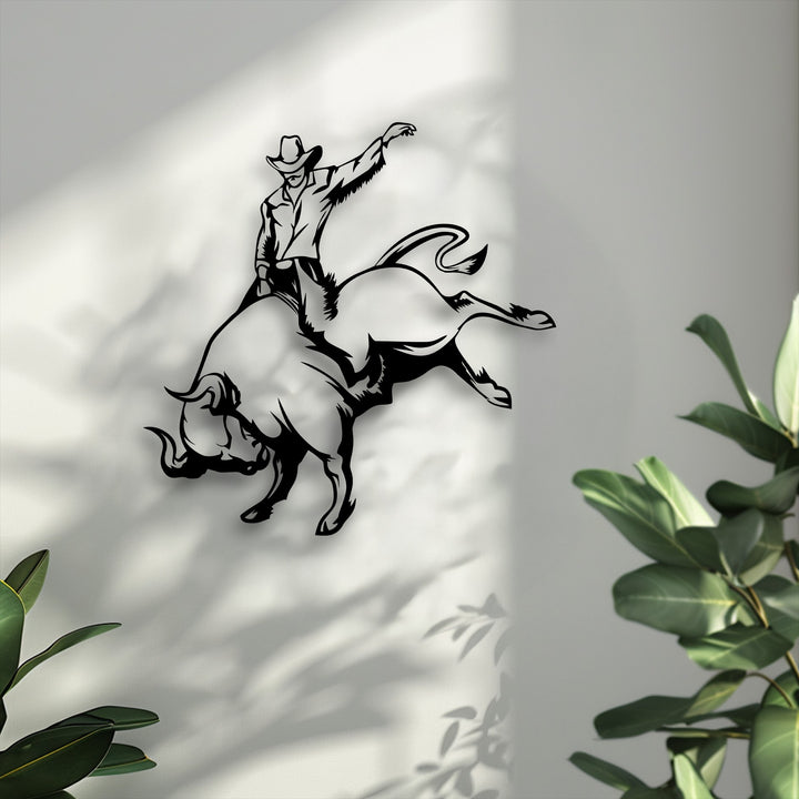 The bright, textured negative space of the wall enhances the dramatic silhouette of the unique metal wall art depicting a cowboy bull riding.
