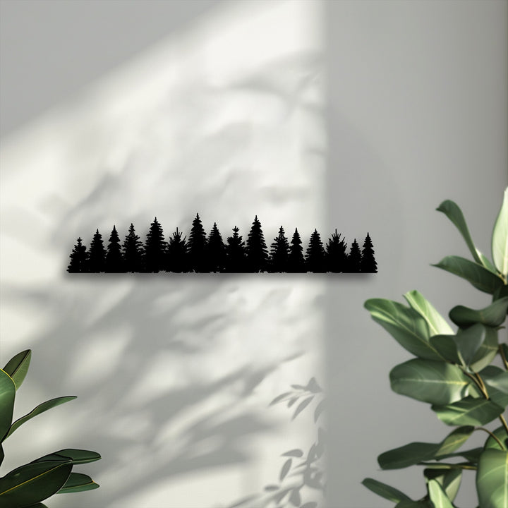The subtly textured wall highlights the smooth, matte black surface of the pine forest silhouette decorative metal art.