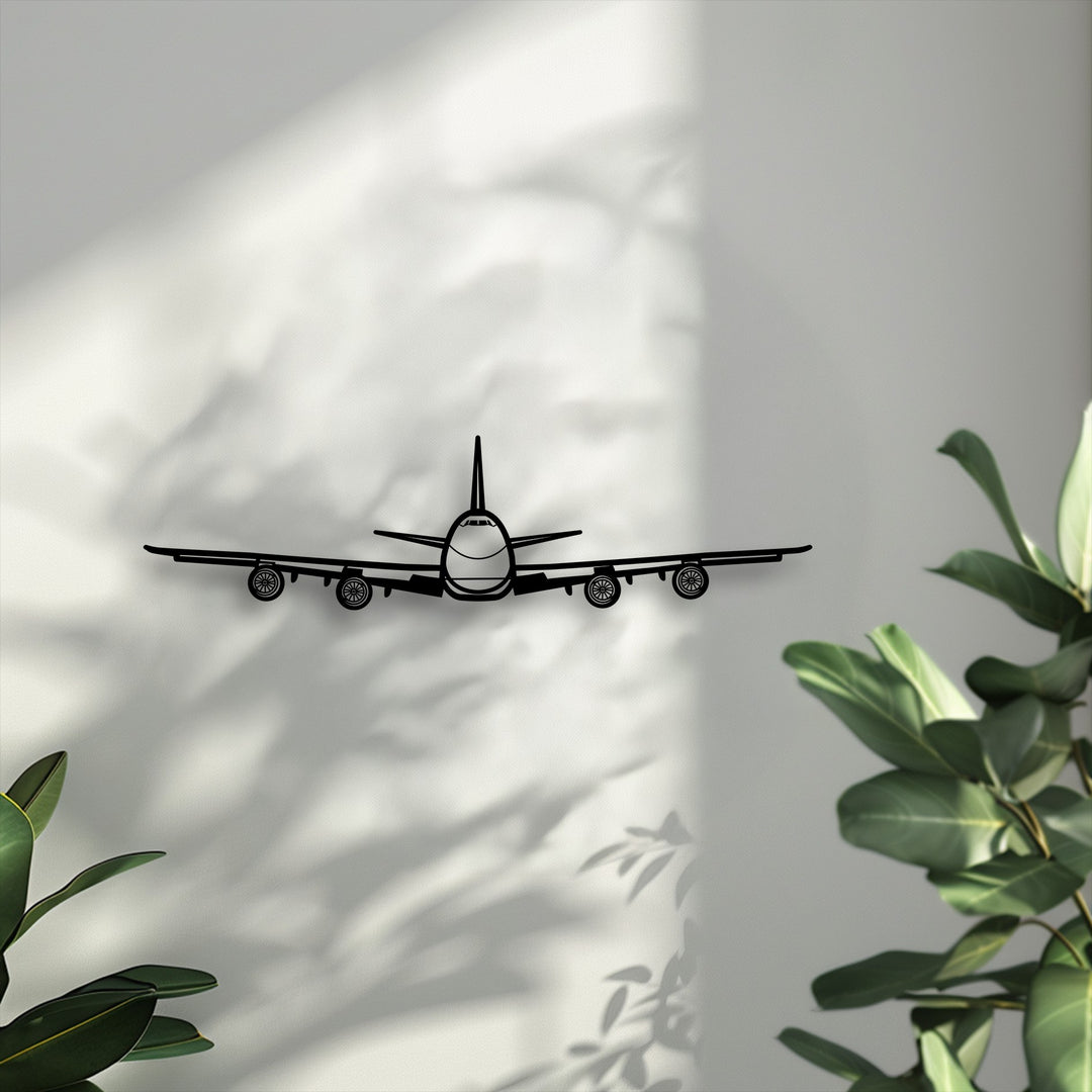 Negative space on the bright, shadowed wall defines the bold black airplane front view, creating impactful unique metal wall art aviation decor.