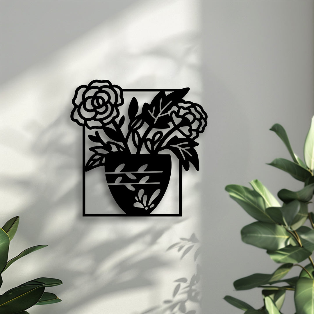 The focal point is a striking black metal artwork depicting a blooming floral vase silhouette against a sunlit white wall with plant shadows.