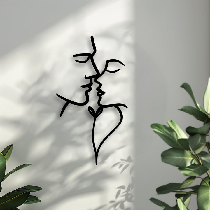 The abstract quality of this black line metal wall decor artfully depicts two faces kissing, forming a heart at their base.