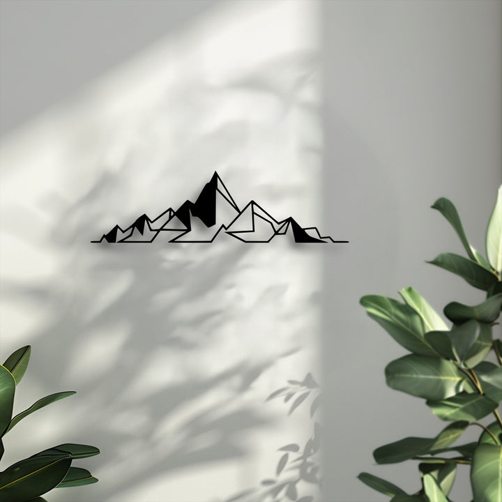 The geometric mountain metal wall decor presents striking depth through its layered silhouette and intricate shadows it projects on the white wall.