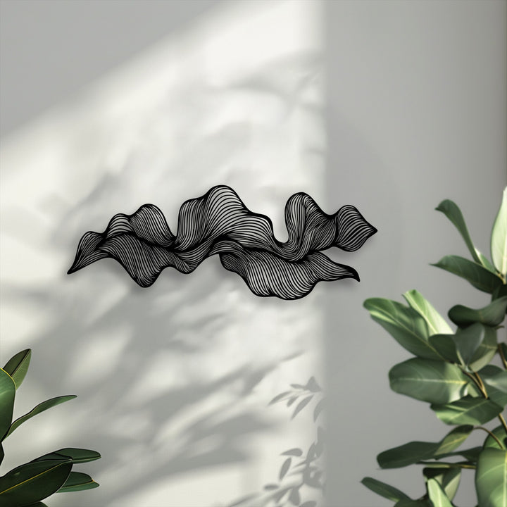 The elegant transition between the black abstract wave flow decorative metal art and the lightly shaded wall offers a subtle play of colors.