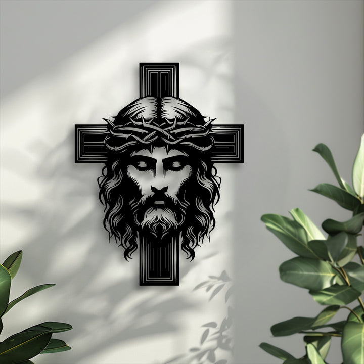 The crisp, bold edges and distinct borders of the black Sacred Cross with Christ metal artwork are sharply defined against the light wall.