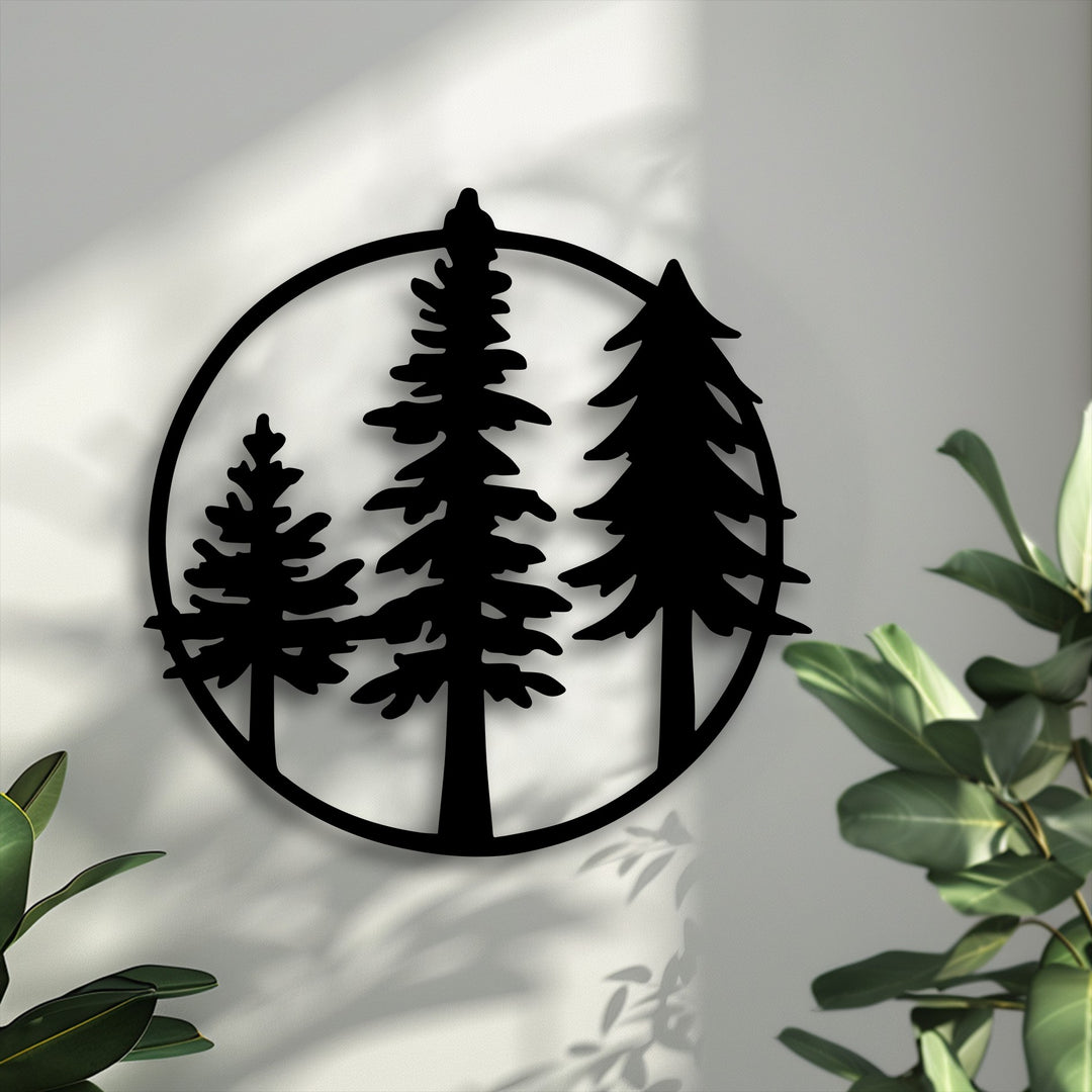 Bold black circular metal art for wall, depicting three silhouetted evergreen pine trees, casts long shadows on a bright wall.