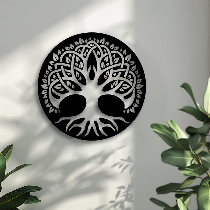 Stillness is palpable around the elegant Celtic Tree of Life decorative metal art, with soft shadows and calm green plant leaves beside it.