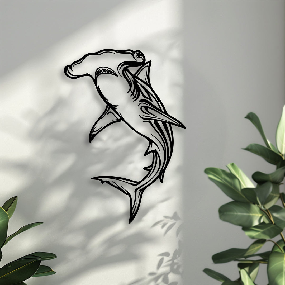 Negative space highlights the hammerhead shark unique metal wall art, with sunlight and leaf shadows casting organic patterns on the pale wall.