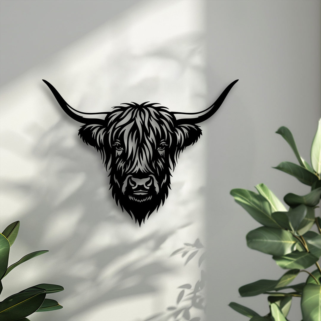 The bright background features soft shadows from leaves cast on a textured white wall, complementing the Highland bull head metal art for wall.