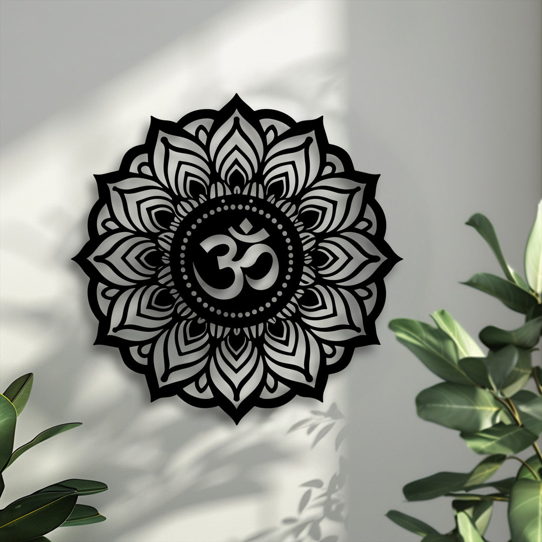 Sunlight casts dramatic light and intricate shadows from the black Sacred Om Mandala metal artwork and lush plants onto a textured white wall.