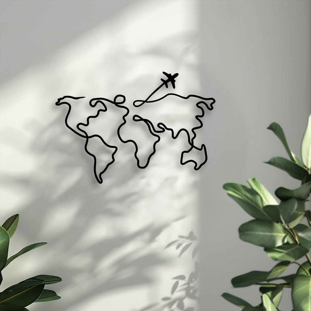 The pristine white wall with soft, dappled shadows serves as a simple backdrop for the minimalist world map metal artwork.