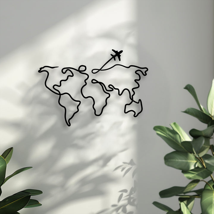 The pristine white wall with soft, dappled shadows serves as a simple backdrop for the minimalist world map metal artwork.