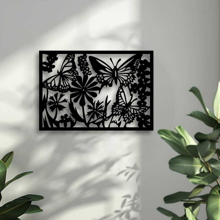 A horizontally oriented, rectangular metal wall decor panel depicts an intricate butterfly and floral nature silhouette.