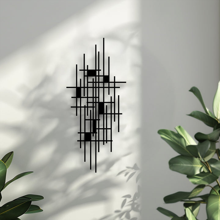 Vertically oriented, abstract geometric grid metal art for wall with a minimalist design of intersecting black lines and rectangular shapes.