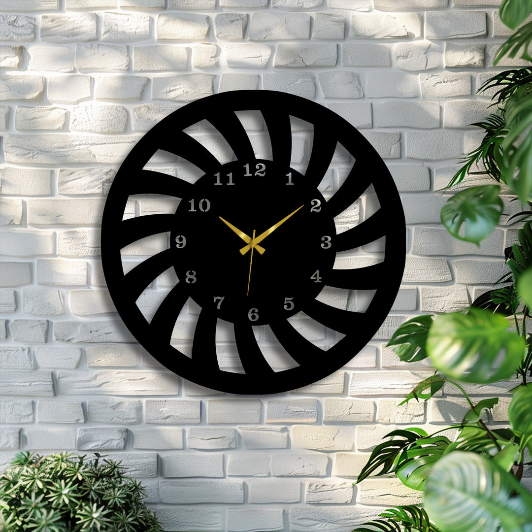 Vibrant green foliage borders a contemporary black spiral metal wall clock with golden hands, a captivating piece of metal artwork.