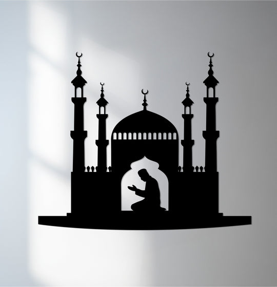 The matte finish of this unique metal wall art highlights the silhouette of a man praying inside a mosque featuring domes and minarets.