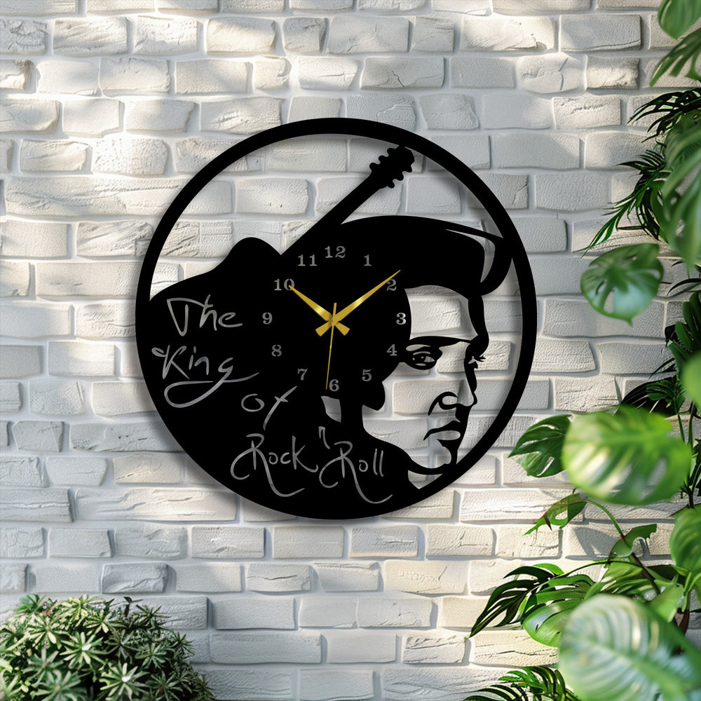 A black metal artwork wall clock, featuring Elvis Presley's guitar, creates layered depth on a white brick wall, framed by green plants.