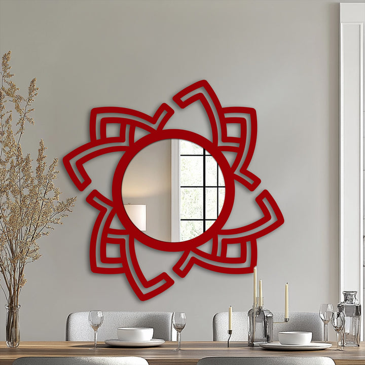 Serving plates, stemware, and a modernist candle display adorn the table in front of the abstract rotating frame unique metal wall art mirror, creating a visually compelling scene.