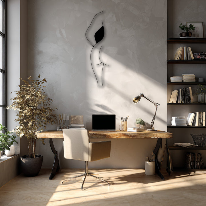 A golden potted plant and a beige chair sit by a wooden desk, bathed in sun on the floor, enhancing the modern metal art for wall.