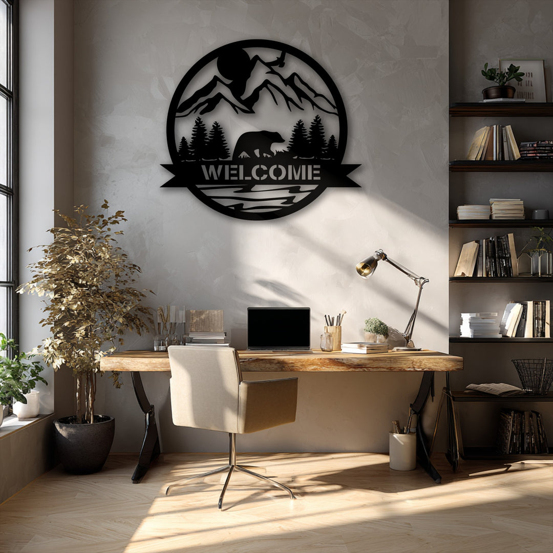 A circular metal artwork is vertically oriented on a wall, showcasing a stylized bear, towering mountains, and a clear welcome sign.