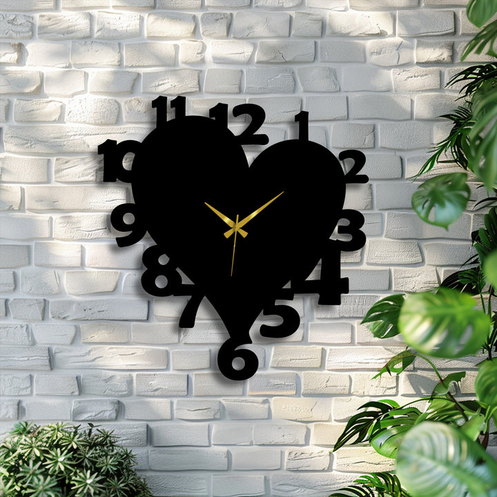 Sharp color contrast defines the black heart shape metal wall clock with gold hands, prominent on a white brick wall, offering striking decoration wall art.