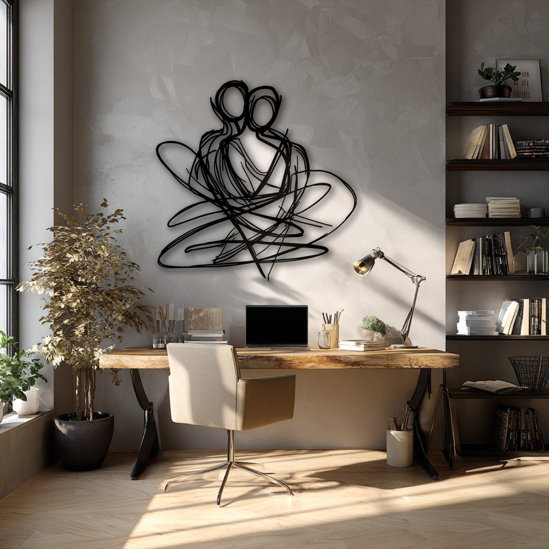 An intricate black abstract couple decorative metal art sculpture with flowing lines on a textured wall, illuminated by sunlight.