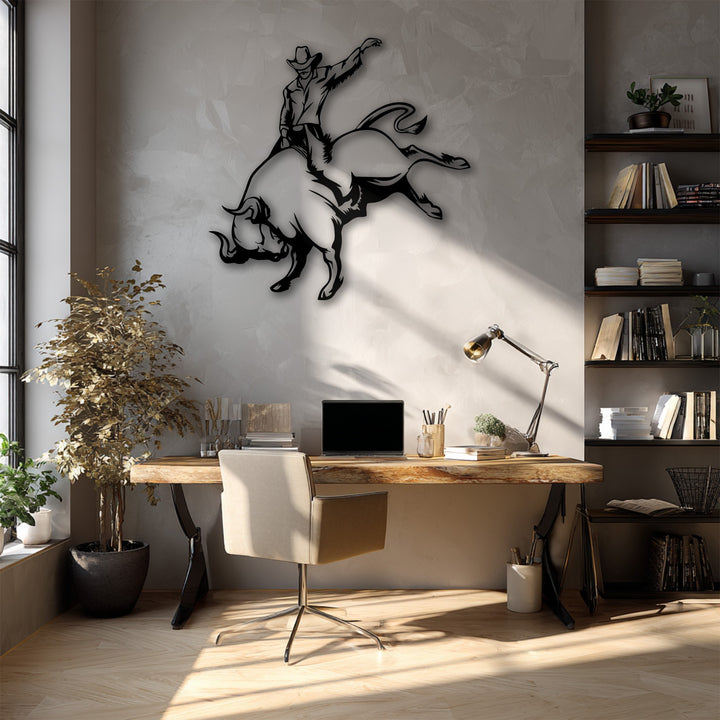 A dynamic silhouette of a cowboy bull riding, forming an asymmetrical metal wall decor piece, oriented horizontally.