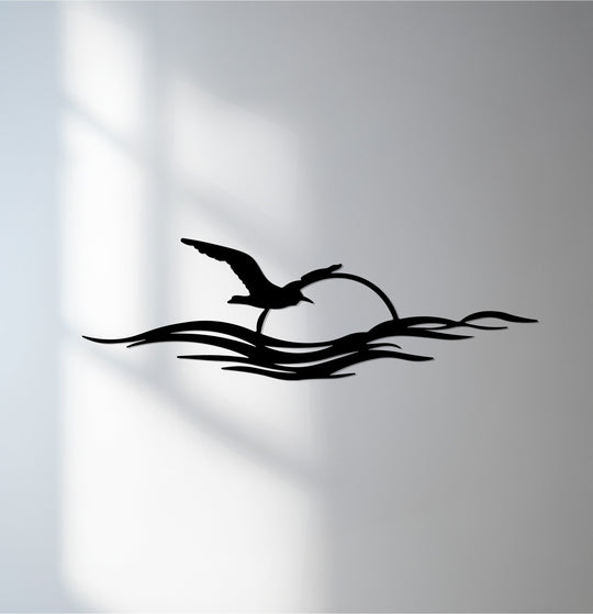 Black is the dominant color in this striking decoration wall art, a seagull flying over a minimalist metal ocean sunset scene.