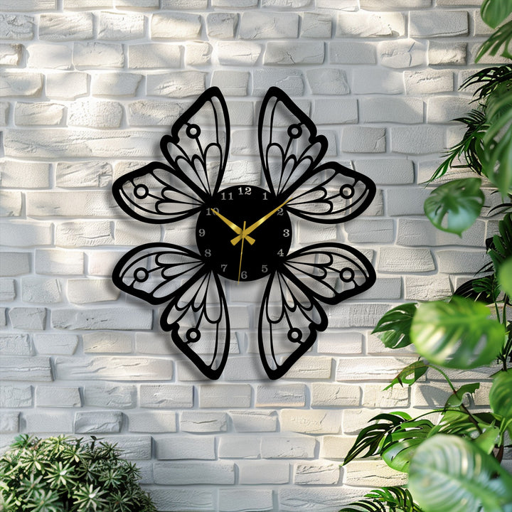 The background features a textured white brick wall illuminated by soft light, complementing the elegant butterfly wings metal artwork clock.