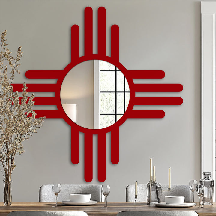 Vertically oriented, bold red modern metal art for wall, distinctly shaped like a stylized Zia sun with a central round mirror.