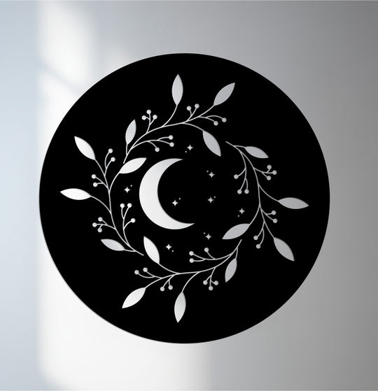 Geometric decoration wall art features a round, black metal piece showcasing a crescent moon and stars encircled by stylized leaf wreaths.