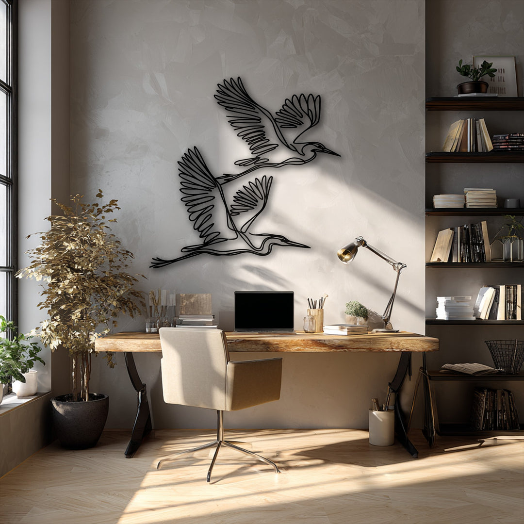 The image features understated color saturation, highlighting two elegant flying herons minimalist metal wall decor pieces against a soft, textured wall.