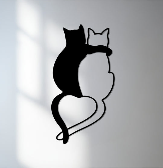 Illuminated by window shadows, the brightest area highlights the negative space between the black and white cats in this minimalist metal artwork forming a heart shape.