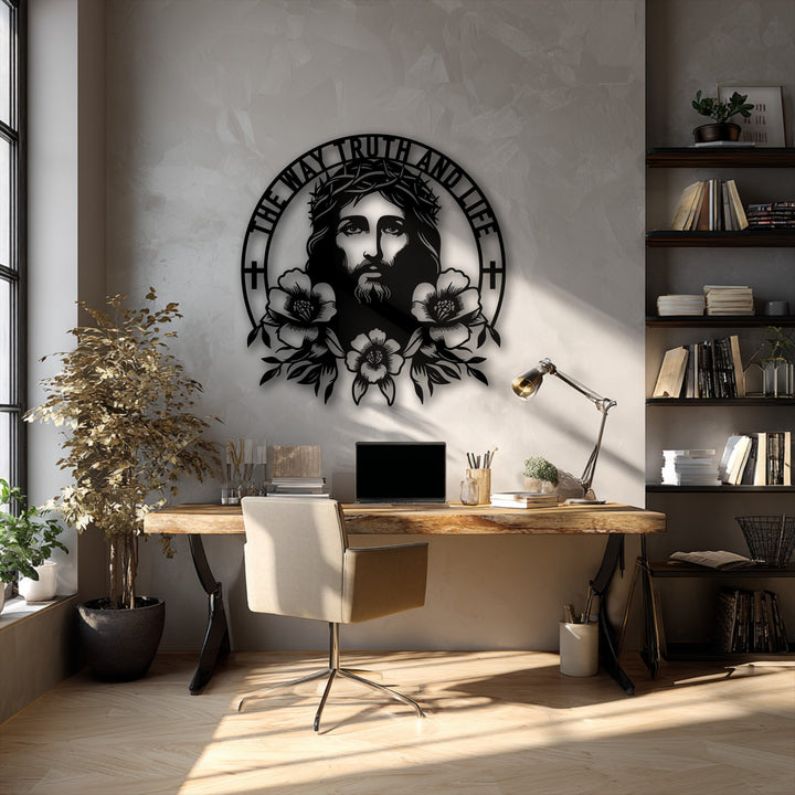 A light wood desk with a laptop and a beige chair occupies the foreground, complementing the detailed Jesus metal artwork.