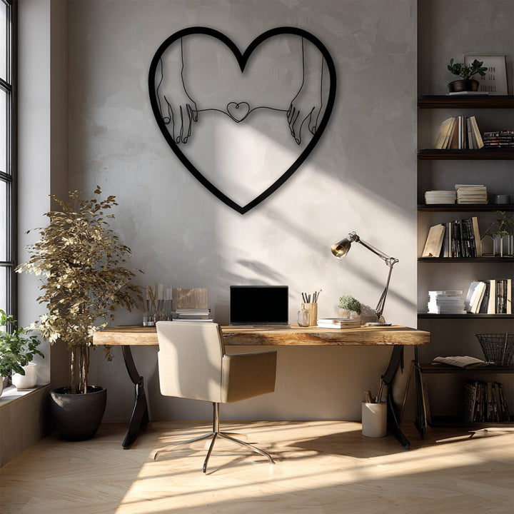 The distinctive matte black finish of the minimalist heart-shaped unique metal wall art featuring connected hands holding a small heart.