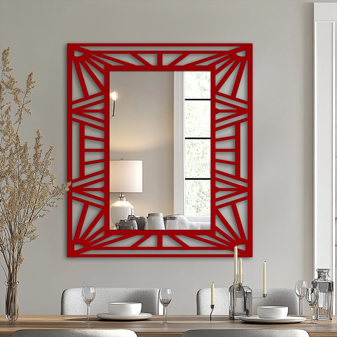 Negative space creates the sunburst pattern within the red geometric frame of this unique stained glass wall mirror, reflecting ambient light and a blurred interior scene.