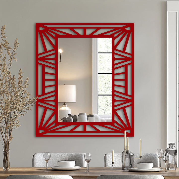 Negative space creates the sunburst pattern within the red geometric frame of this unique stained glass wall mirror, reflecting ambient light and a blurred interior scene.