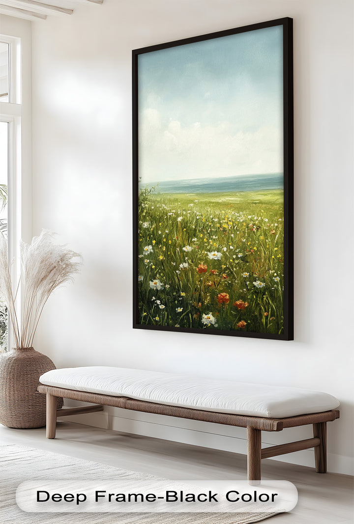 This serene landscape painting captures a sunlit wildflower meadow stretching toward the calm sea under a soft blue sky.