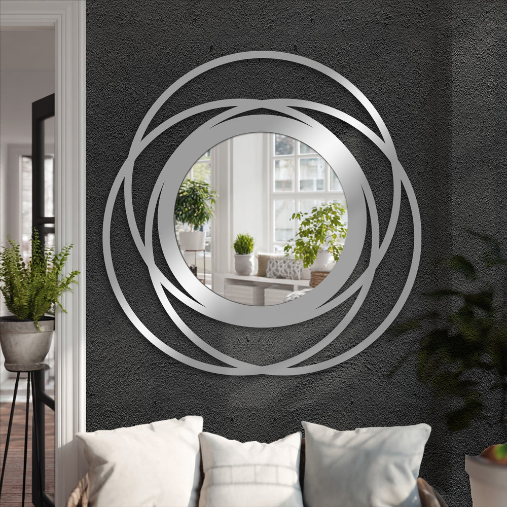 Light and shadow play across the intertwined rings of this striking framed wall mirror, enhancing the modern metal wall decor and its bold circular design.